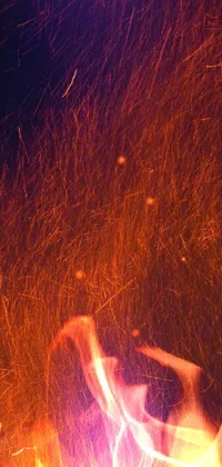 Add a mesmerizing touch of artistic beauty to your phone with a live wallpaper featuring a close-up shot of a person standing in front of a blazing fire