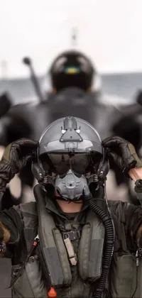This immersive phone live wallpaper depicts a thrilling action shot of a fighter jet and an anonymous man standing in front of it