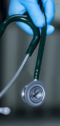 This phone live wallpaper features a close-up image of a stethoscope being held by an anonymous person wearing blue gloves under the night sky