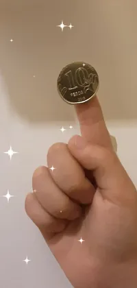 Treat yourself to this stunning live wallpaper featuring a close-up of a hand holding a shiny coin with intricate details