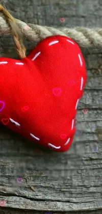Looking for a charming and whimsical live wallpaper for your phone? Check out this dynamic red heart hanging from a rope on a piece of wood, swaying back and forth against a peaceful boat background