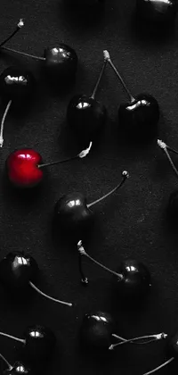 This live wallpaper for phones features a photograph of red cherries on a black backdrop