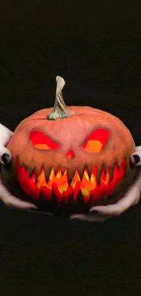 This spooky phone live wallpaper portrays a frightening scene with a pumpkin sporting a scary face which is being tightly held by a mysterious figure