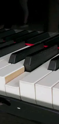 This live phone wallpaper showcases a close-up of a classic piano, featuring a mesmerizing black and white keyboard with distinguishing red keys