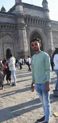 This stunning live wallpaper displays a man wearing sunglasses and casual attire, standing in front of a towering building