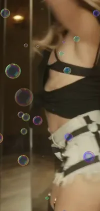 This chic live wallpaper displays a stylish woman admiring herself in a mirror while colorful bubbles drift in the background