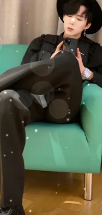 This phone live wallpaper depicts a man sitting on a green chair surrounded by an album cover