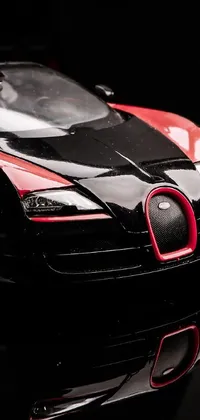 This phone live wallpaper showcases a hyperrealistic Bugatti Veyron toy car in a striking red on black color scheme