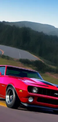 This live phone wallpaper features a stunning digital rendering of a red car driving down a winding road