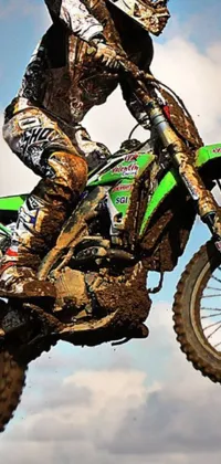 This dynamic phone live wallpaper features a dirt bike rider soaring through the air on a metallic green bike, captured in close-up detail