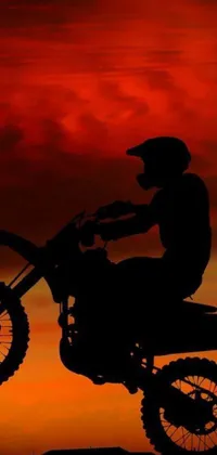 Get your adrenaline pumping with this exciting phone live wallpaper! Featuring a dirt bike rider racing against the setting sun, this high-resolution background packs a thrill