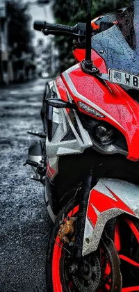 Enjoy the thrill of the open road with this phone live wallpaper featuring a red and black motorcycle parked on a wet city street