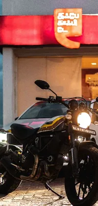 Looking for a phone live wallpaper that oozes style, adventure, and excitement? Check out this stunning image of a scrambler motorcycle parked in front of a gas station with a transparent black windshield