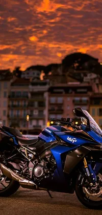 This live wallpaper for phones depicts a realistic blue motorcycle parked beside a road with a rich city sunset in the backdrop
