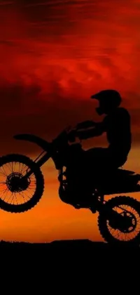 Looking for a lively and vibrant phone live wallpaper? Check out this stunning design depicting a dirt bike rider in action against a beautiful red sunset backdrop