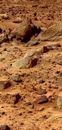 This mesmerising phone live wallpaper depicts a group of rocks resting on a sandy expanse, awash in bright red desert sands