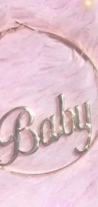 This phone live wallpaper features a close-up of a delicate necklace with the word "baby" on it, surrounded by a transparent, pastel-themed design with a floral design in the background