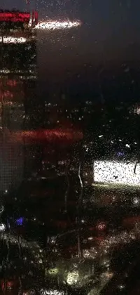 This live wallpaper features a stunning view of a city at night through a rain-splattered window