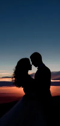 Enhance your mobile device's appearance with a stunning live wallpaper featuring a bride and groom standing on a mountain peak at sunset