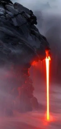 This stunning phone live wallpaper depicts a breathtaking image of molten lava flowing down a rugged cliff face and into the depths of the ocean