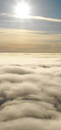 This phone live wallpaper portrays an airplane soaring high above fluffy blankets of fog pockets and golden clouds