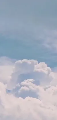 This phone live wallpaper showcases a jetliner flying amidst fluffy clouds in a blue sky