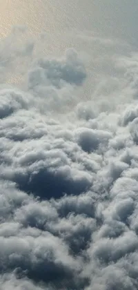 This stunning phone live wallpaper showcases a bird's eye view of an airliner flying high above mollifying, mammatus clouds over the vast oceans