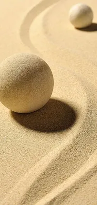Looking for a serene and minimalist phone wallpaper? Check out this live background featuring two rocks on a sandy beach