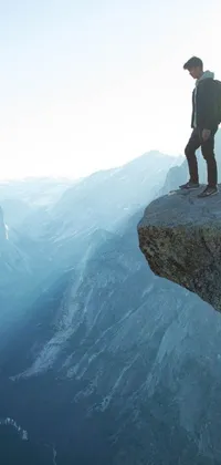 This live wallpaper features a stunning image of a person standing on a cliff, backpack on their back, lost in thought