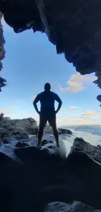 This live wallpaper features a spectacular photograph taken in 2020, showcasing a figure standing at the end of a cave, with the ocean in the background