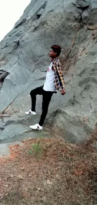 This phone live wallpaper features a stunning image of a man standing on a rocky terrain