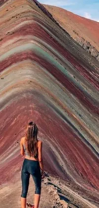 This live phone wallpaper showcases a woman on top of a mountain in a color field background