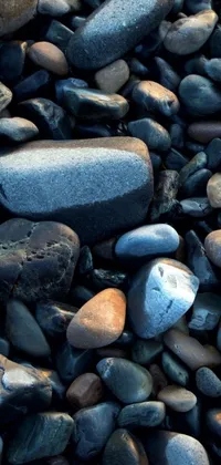 This phone live wallpaper depicts a photorealistic scene of a pile of rocks sitting on a sandy beach