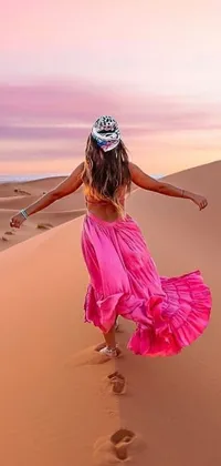 This live wallpaper features a gorgeous image of a woman in a flowing pink dress as she walks across a sandy desert