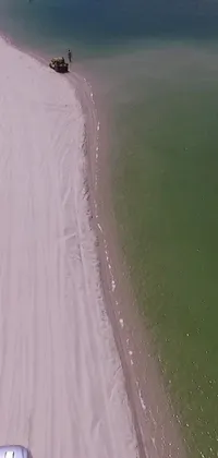 This phone live wallpaper depicts a stunning scene of a car driving down a beach beside a body of water