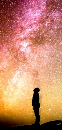 Looking for an amazing live phone wallpaper? Look no further than this stunning image! Featuring a silhouette of a person standing on a hill under a sky full of stars, this wallpaper brings light and space right to your phone