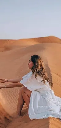 This stunning live phone wallpaper depicts a scene of a woman on a sand dune in the Arabian desert