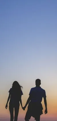 This phone live wallpaper features a romantic image of a couple walking away in profile view as the sun sets behind them