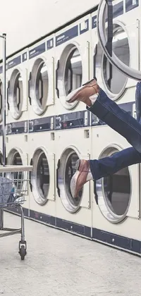 This phone live wallpaper showcases a playful, post-processed stock photo of a person jumping in front of a row of washing machines