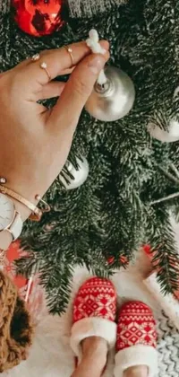This phone live wallpaper features a striking Christmas scene, showcasing a stunning ornament and a lush tree adorned with several decorations