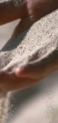 This nature-inspired live wallpaper features a close-up shot of someone holding fine sand on their palms, creating a subtle, calming effect