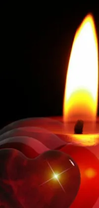 This live wallpaper depicts a candle with a heart design on its flame, set against a black background