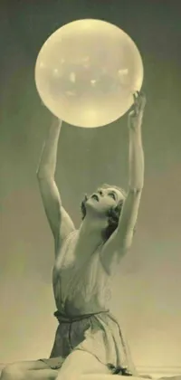 This stunning black and white phone live wallpaper features a photograph of a gorgeous woman holding a frisbee and a glowing orb, creating a magical atmosphere