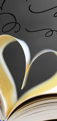 This phone live wallpaper showcases a heart cut out of a book, revealing an enchanting image
