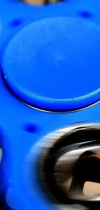 This lively and captivating phone live wallpaper features a stunning blue fidget spinner spinning atop a table, with a tightly cropped, middle close-up shot showcasing the spinner's every detail