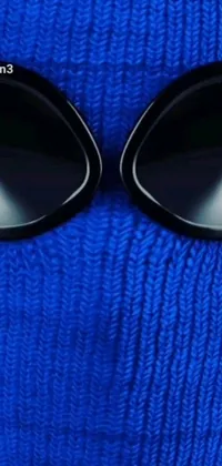 This stunning phone live wallpaper showcases a minimalist close-up of a person wearing stylish shades, set against a blue-fabric backdrop that evokes wintertime vibes