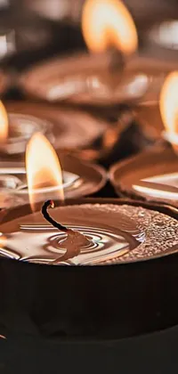 This live wallpaper depicts a group of lit candles on a table, casting reflections in copper