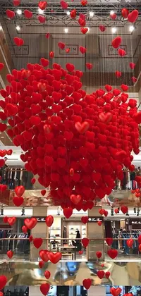 This stunning phone live wallpaper showcases a bunch of red heart-shaped balloons suspended from a ceiling