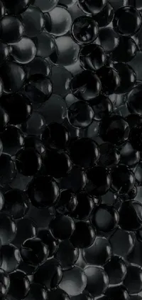 This striking live wallpaper features a close-up of black beads arranged in a circular pattern, set against a glass-like texture