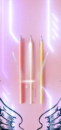 This live phone wallpaper features two pencils on a pink surface with beautiful angelic wings in the corner